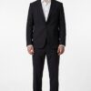 Man in a tailored black suit with a white dress shirt and brown shoes, standing straight against a white background.