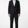 Man wearing a black two-piece suit with a white dress shirt and brown shoes, standing against a white background.