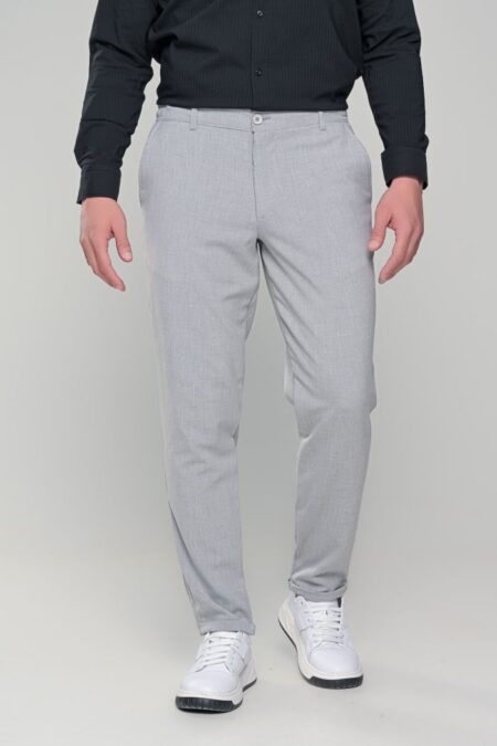 Man standing in a black shirt and light gray dress pants with white sneakers, showcasing a smart-casual outfit.