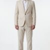 Man in a light beige suit with a white shirt and brown dress shoes, standing against a white background.