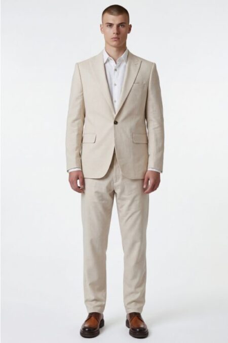 Male model wearing a light beige two-piece suit with a white shirt and brown loafers, standing straight against a white background.