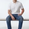 Man sitting on a wooden bench, wearing a white polo shirt, blue jeans, and white sneakers, facing forward.”] ,