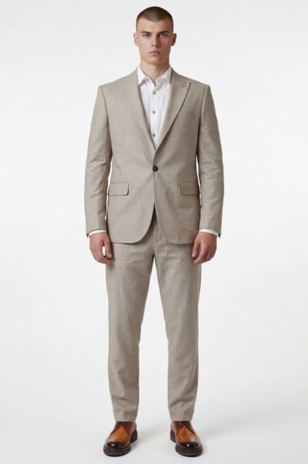 Man wearing a light beige two-piece suit with a white dress shirt and brown loafers, standing against a white background.