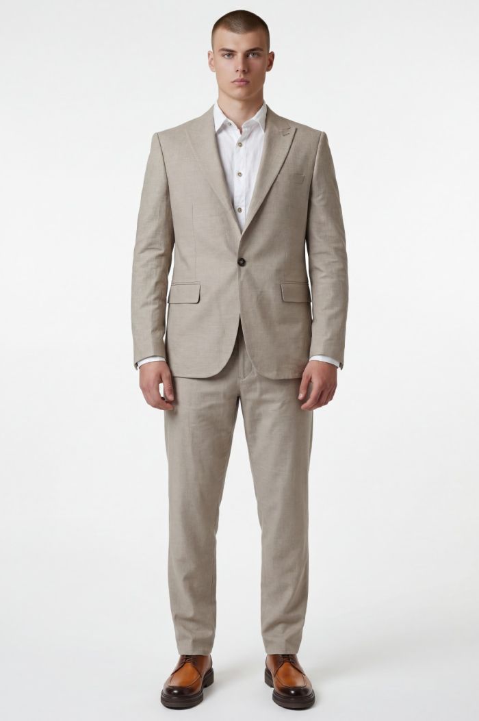 Man in a light beige suit with white shirt, standing and facing the camera.