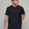 Man wearing a black short-sleeve T-shirt and beige pants, standing and smiling against a neutral gray background (product photo).