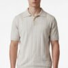 Man wearing a beige ribbed polo knit shirt with short sleeves, standing against a white background.