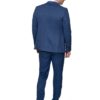 Back view of a man in a blue suit, standing with hands at his sides, wearing brown shoes.