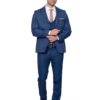 Man in a blue suit adjusting his sleeve, wearing a white shirt and tan tie, standing against a white background.