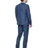 Man in a blue suit seen from behind, walking to the right, with brown shoes.