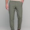 Full-length shot of a man wearing slim-fit olive chinos, a beige shirt, and brown leather shoes, with one hand in pocket.