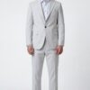 Man in a light gray suit with a single-button blazer, light blue shirt, matching trousers, and white sneakers in a studio.