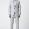 Man in a light gray suit (blazer and trousers) with a pale blue shirt and white sneakers, standing in a studio.