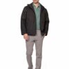 Man wearing a black jacket over a green polo, gray pants, and white sneakers, standing against a white background (full-body portrait).