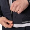 Person unzipping a navy blue jacket, with a light gray shirt visible underneath.