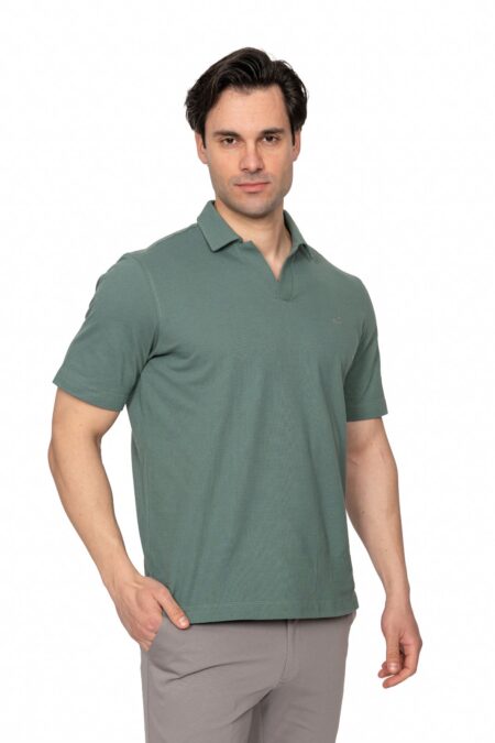 Male model wearing a muted green polo shirt against a white studio background, posing with one hand in his pocket.