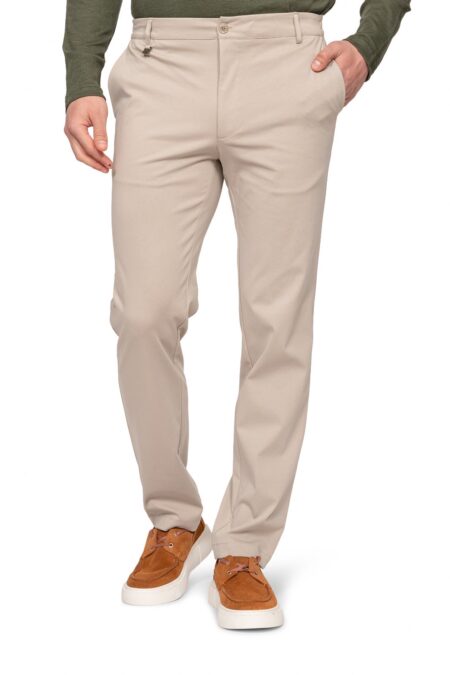 Beige men's chinos with hands in pockets, paired with brown suede sneakers and a dark green top (full outfit view).