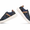 Pair of navy blue sneakers with brown suede detailing and white midsoles, shown floating on a white background with laces tied.
