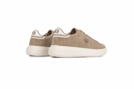Beige sneaker with a white chunky sole, perforated side panels, and stitched branding on the side; back heel tab shows '83' on a light panel; casual athletic shoe look.
