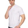 Man in a white polo shirt looks down, adjusting his collar with his left hand while his right hand rests in his pocket.