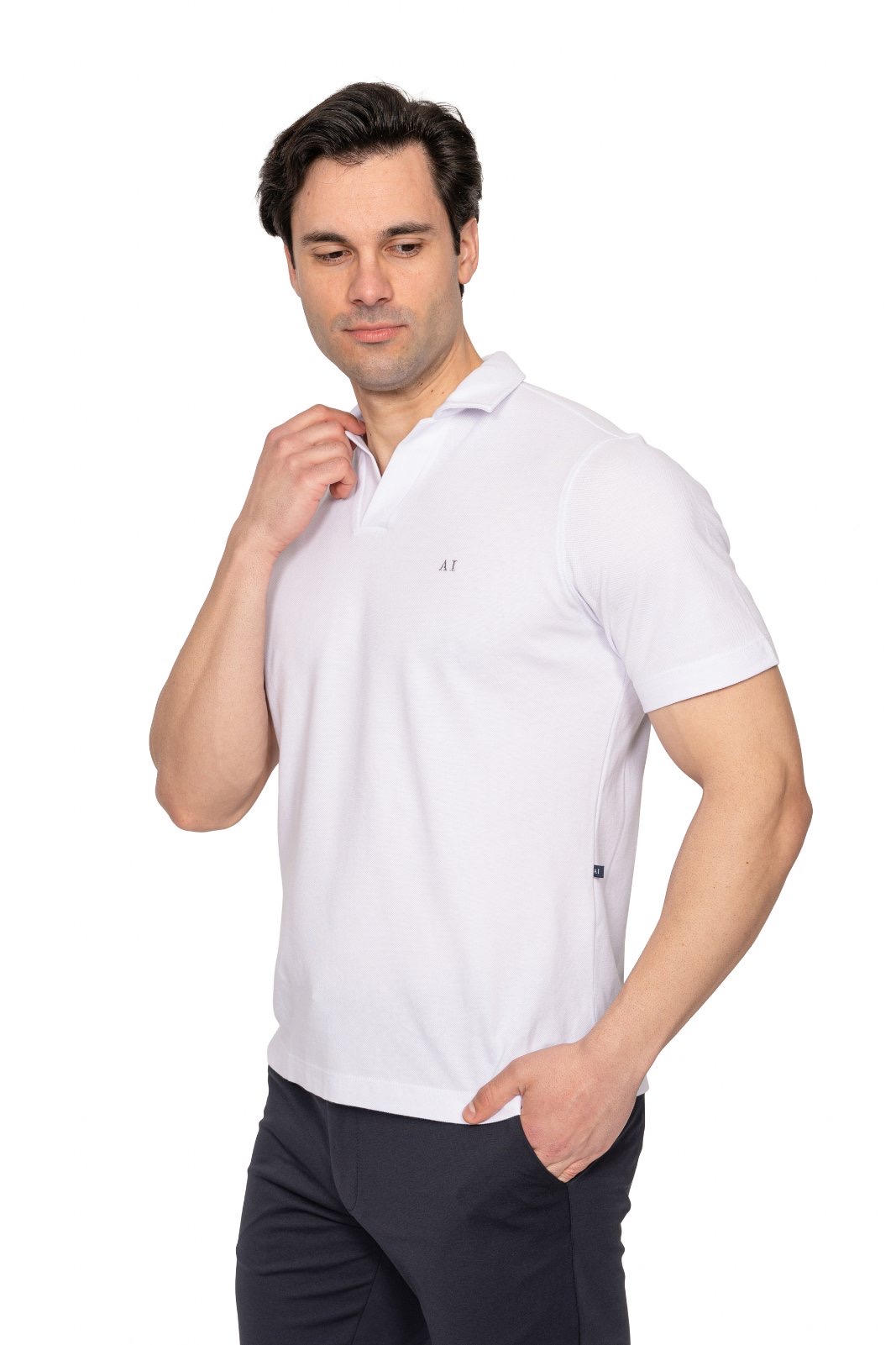 IMG_4978jpg - Noble Man in a white polo shirt looks down, adjusting his collar with his left hand while his right hand rests in his pocket.