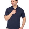 Man in a navy polo shirt smiles softly while adjusting his collar with his right hand, standing against a white background.