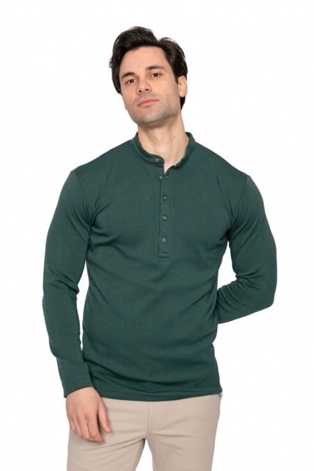Man wearing a dark green long-sleeve henley shirt and beige pants, standing against a white background, looking at the camera.