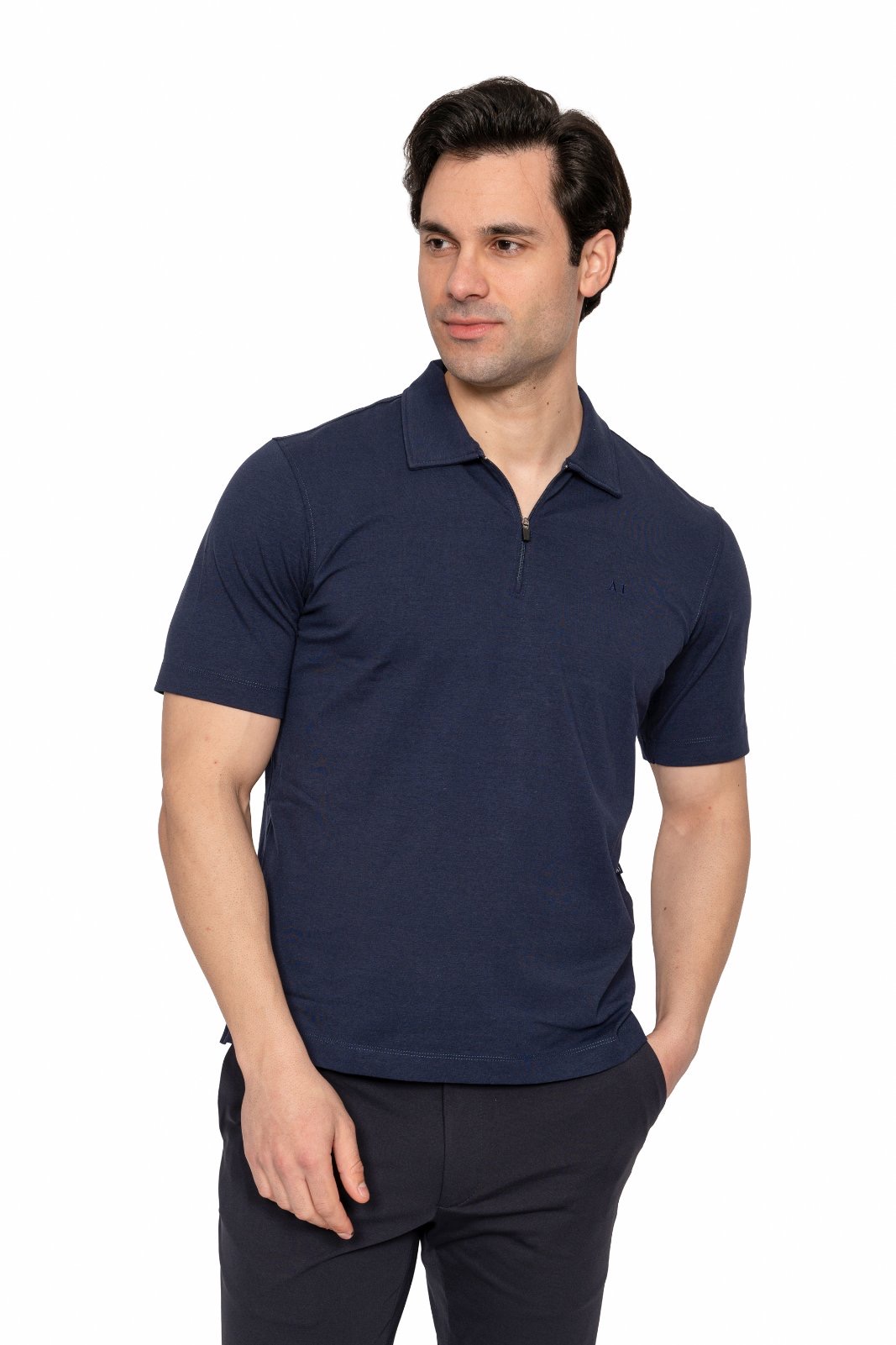 IMG_5010jpg - Noble Man wearing a navy polo shirt and dark pants, standing against a white background, looking to the side.