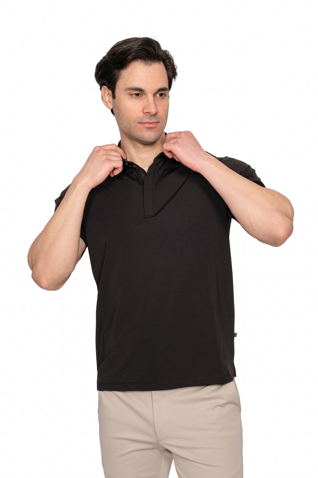 IMG_5031jpg - Noble Man in a black polo shirt adjusts his collar while looking to the side against a white background
