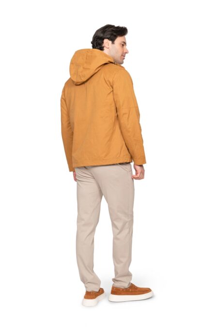 Back view of a man wearing a caramel hooded jacket with beige pants, standing outdoors