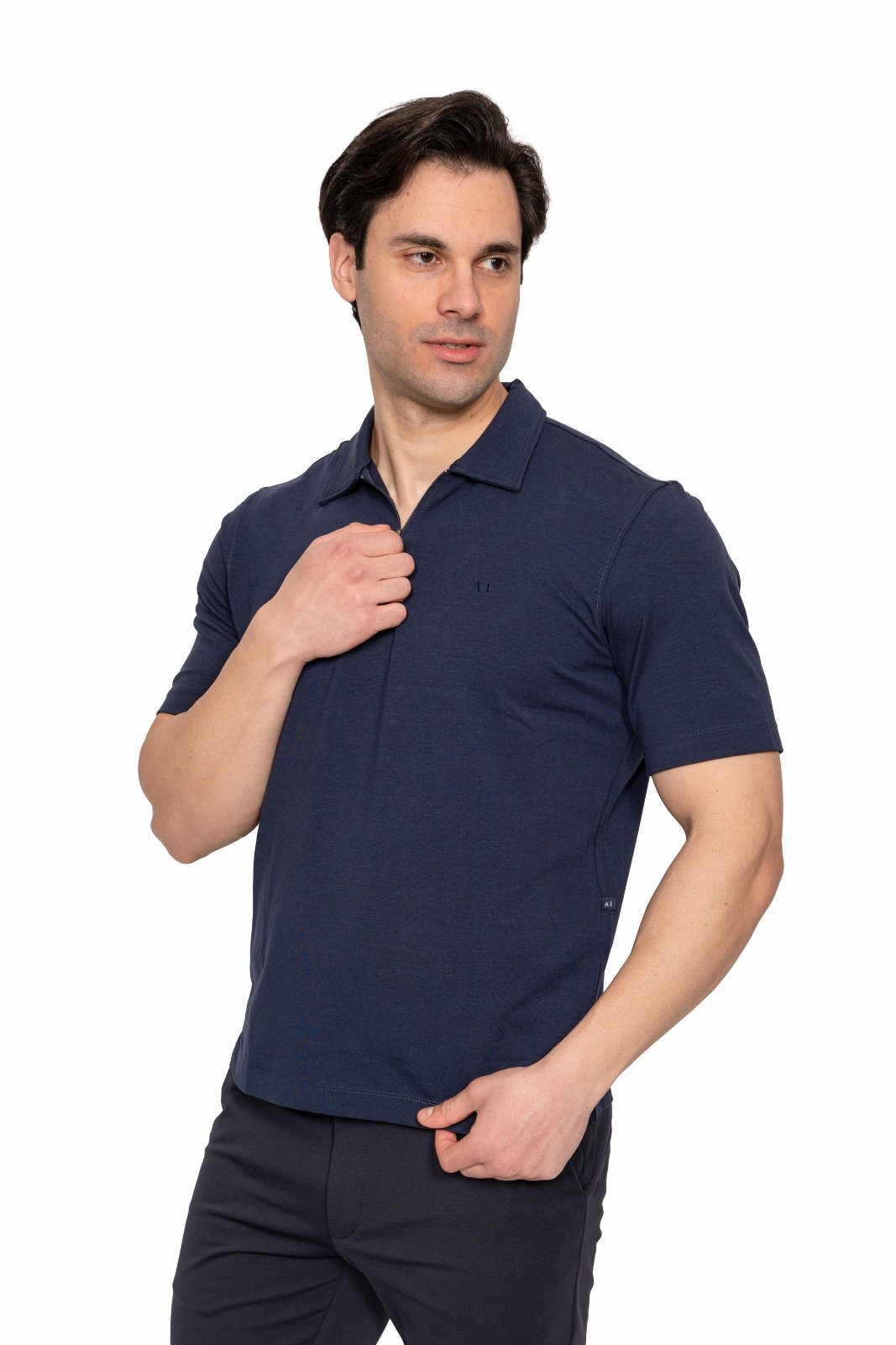 IMG_5065jpg - Noble Man wearing a navy polo shirt, looking to the side with one hand near his chest against a white background.
