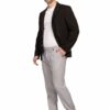 Man in a black blazer, white tee, and light gray trousers poses casually with one hand in pocket, white sneakers.