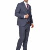 Man in a blue three-piece suit with brown dress shoes, standing and adjusting his jacket.