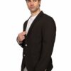 Man in a dark brown blazer over a white shirt, posing with one hand at the lapel against a white background and looking to the side.