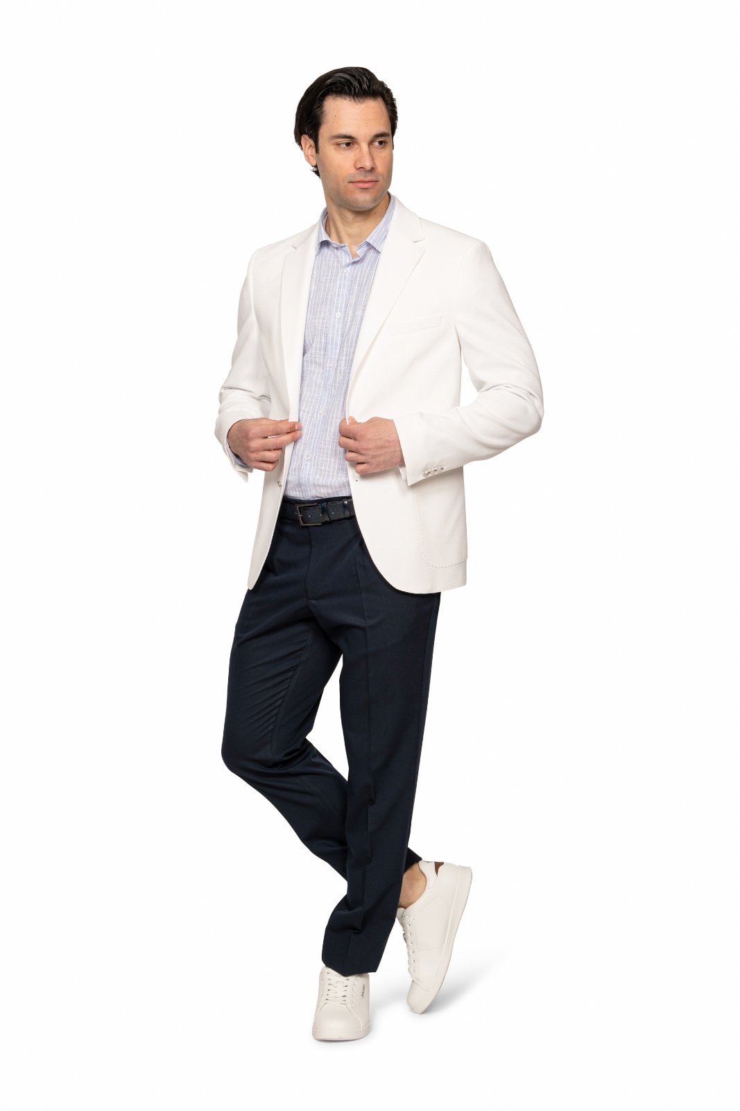 IMG_5150jpg - Noble Man in a white blazer, light shirt, navy trousers, and white sneakers posing with hands on his blazer.