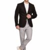 Man in a black blazer, white T-shirt, light gray trousers, and white sneakers posing against a white background, smiling.