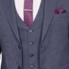 Close-up of a dark gray-blue three-piece suit with a vest, white shirt, pink polka-dot tie, tie bar, and matching pocket square as a formal outfit detail.