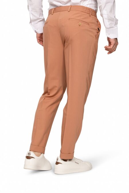 Back view of a person wearing tan chinos, a white shirt, and white sneakers.