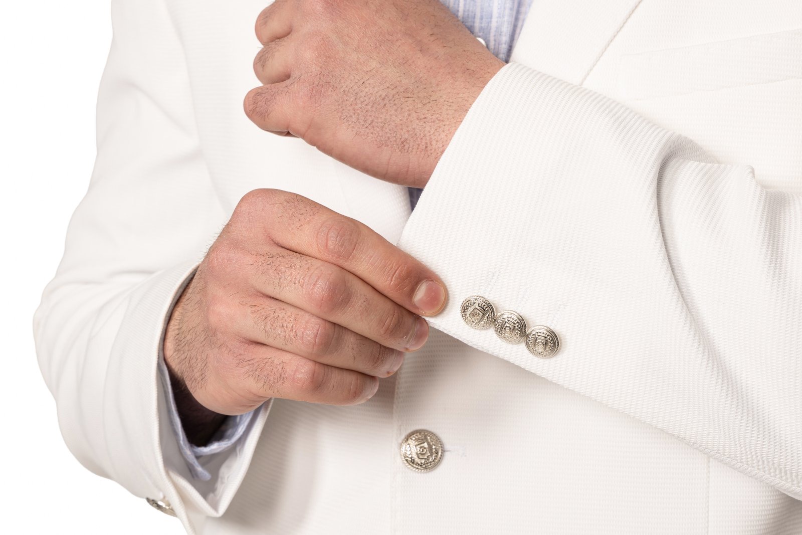 IMG_5243jpg - Noble Close-up of a person in a white suit adjusting the cuff with silver decorative cufflinks.