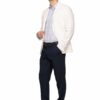 Man wearing a white blazer, light striped shirt, navy trousers, and white sneakers, posing with one hand on his jacket.