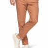 Man wearing tan chinos with a white shirt and white sneakers, standing with one leg crossed.