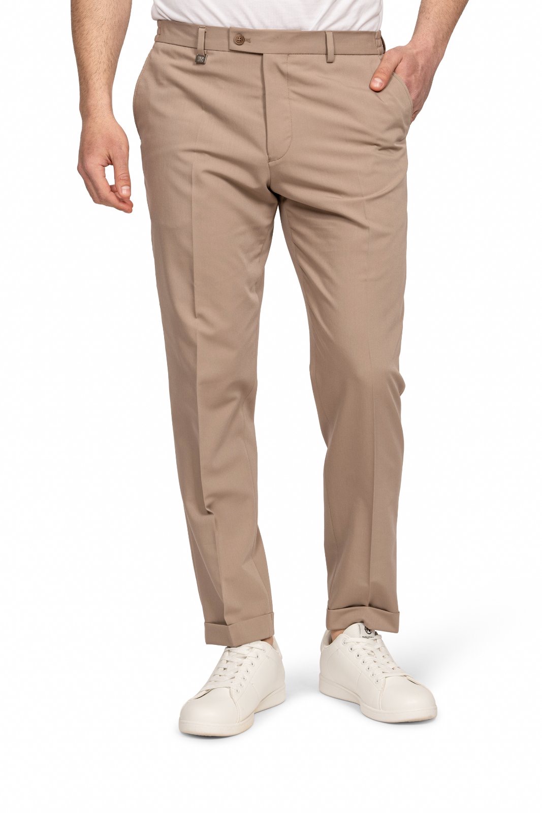 IMG_5255jpg - Noble Beige chinos with a white shirt and white sneakers; person standing with one hand in pocket on white background.